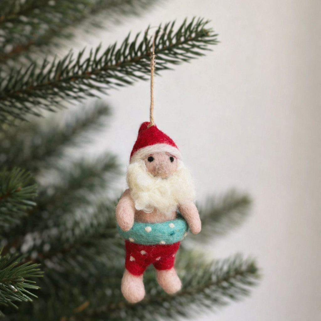 Needle felted Santa Claus ornament with light blue swim ring hanging on a Christmas tree branch.