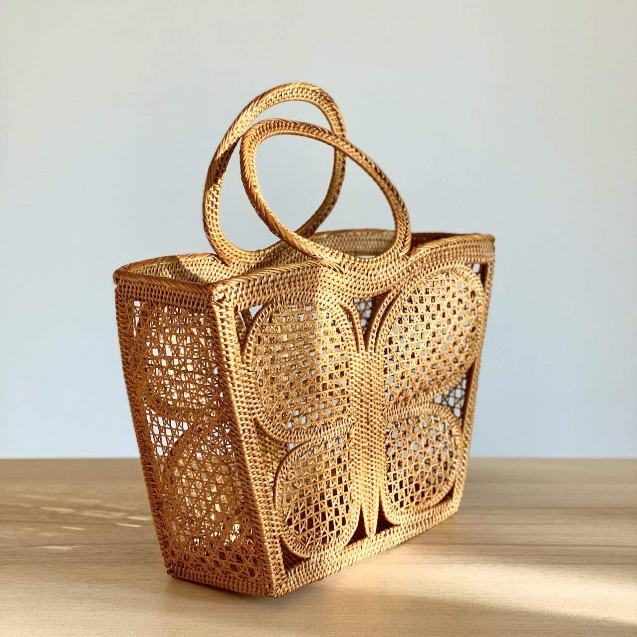 The Butterfly Rattan Handbag handmade by Ganapati Crafts Co. in Bali is sitting on a table looking stylish