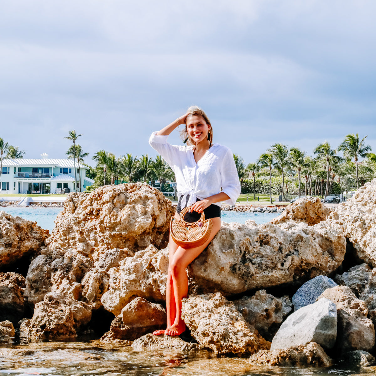 The Tulip Bali Rattan Clutch handmade by Ganapati Crafts Co. in Bali where all the Bali Rattan Bags are made is hold on a young females's arm looking stylish