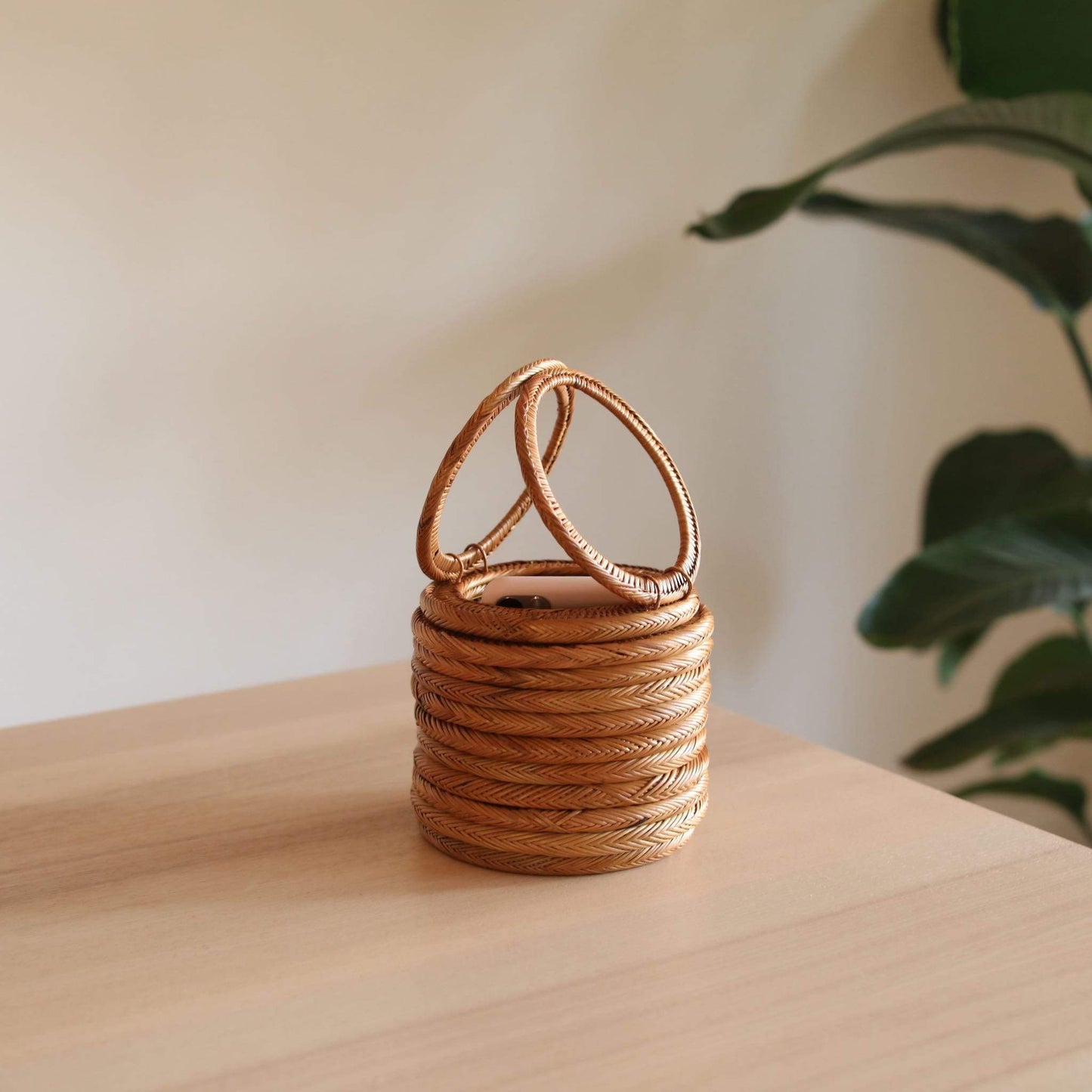 Bali Round Rattan Clutch handmade by Ganapati Crafts Co. in Bali is sitting on a wood table looking stylish and instagramable