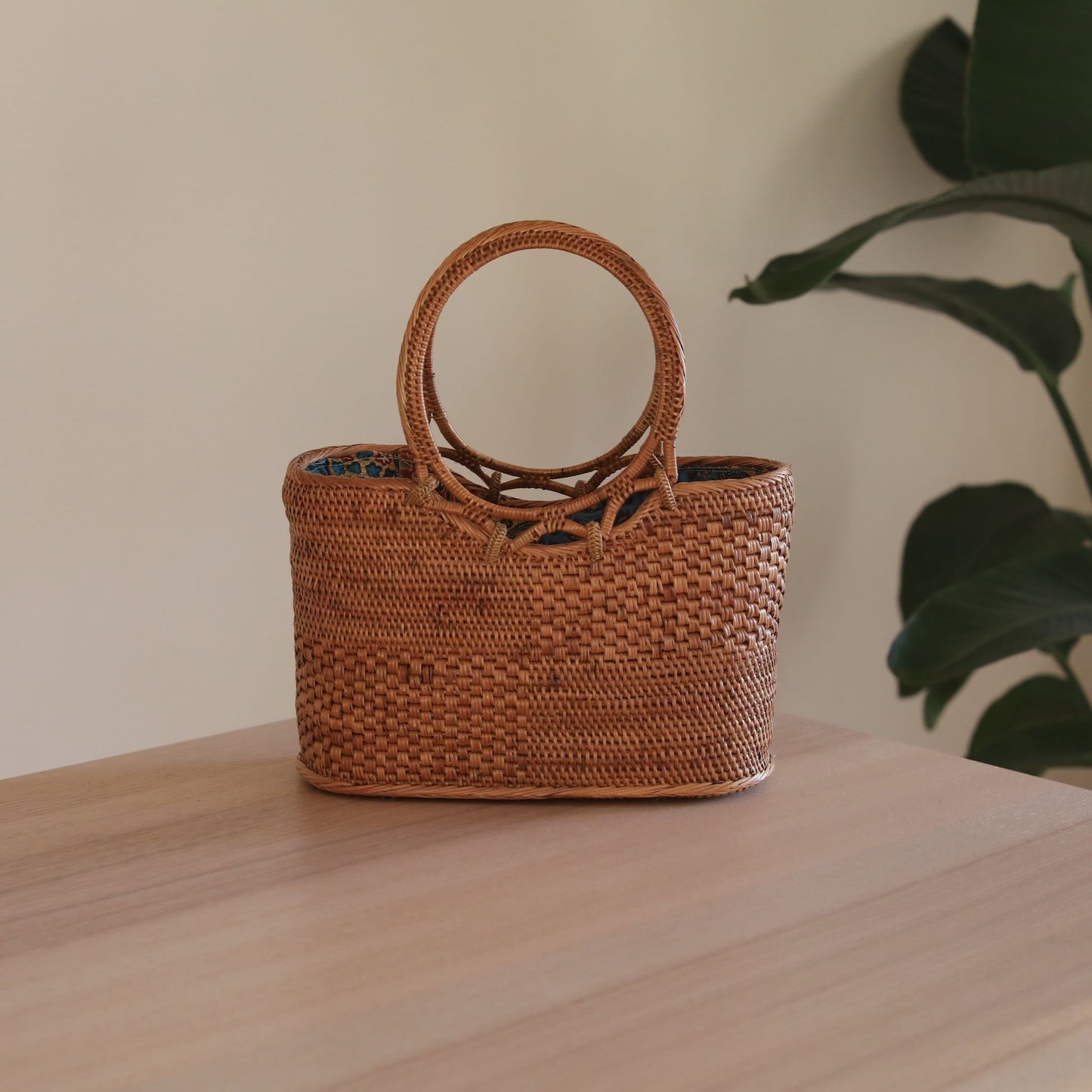 The Kelsey Bali Rattan Handbag handmade by Ganapati Grafts in Bali where all the Bali Rattan Bags are made is sitting n a table looking stylish