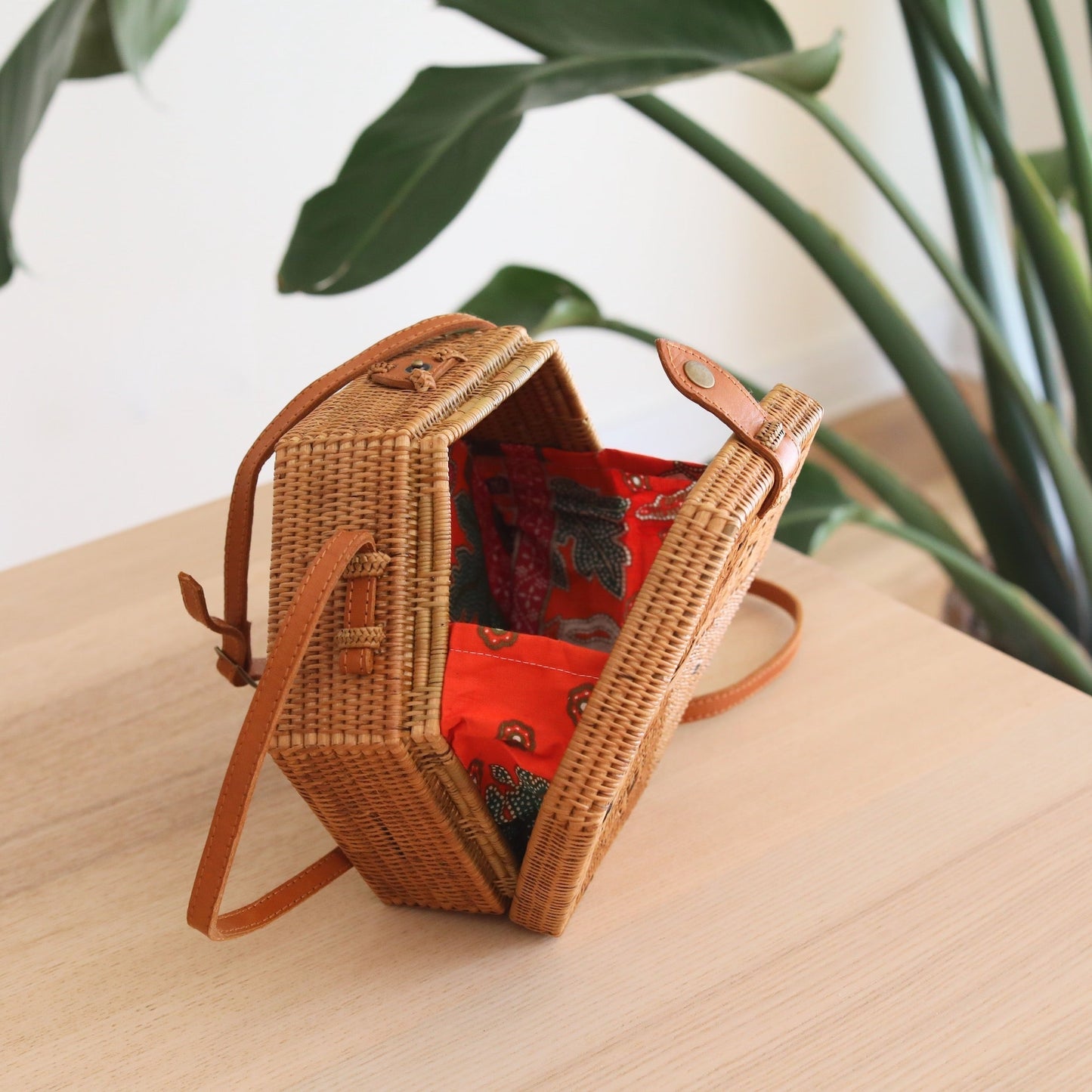 Bali Hexagon Rattan Crossbody Bag by Ganapati Crafts Co. handwoven by skilled artisans in Bali is sitting on a wood table