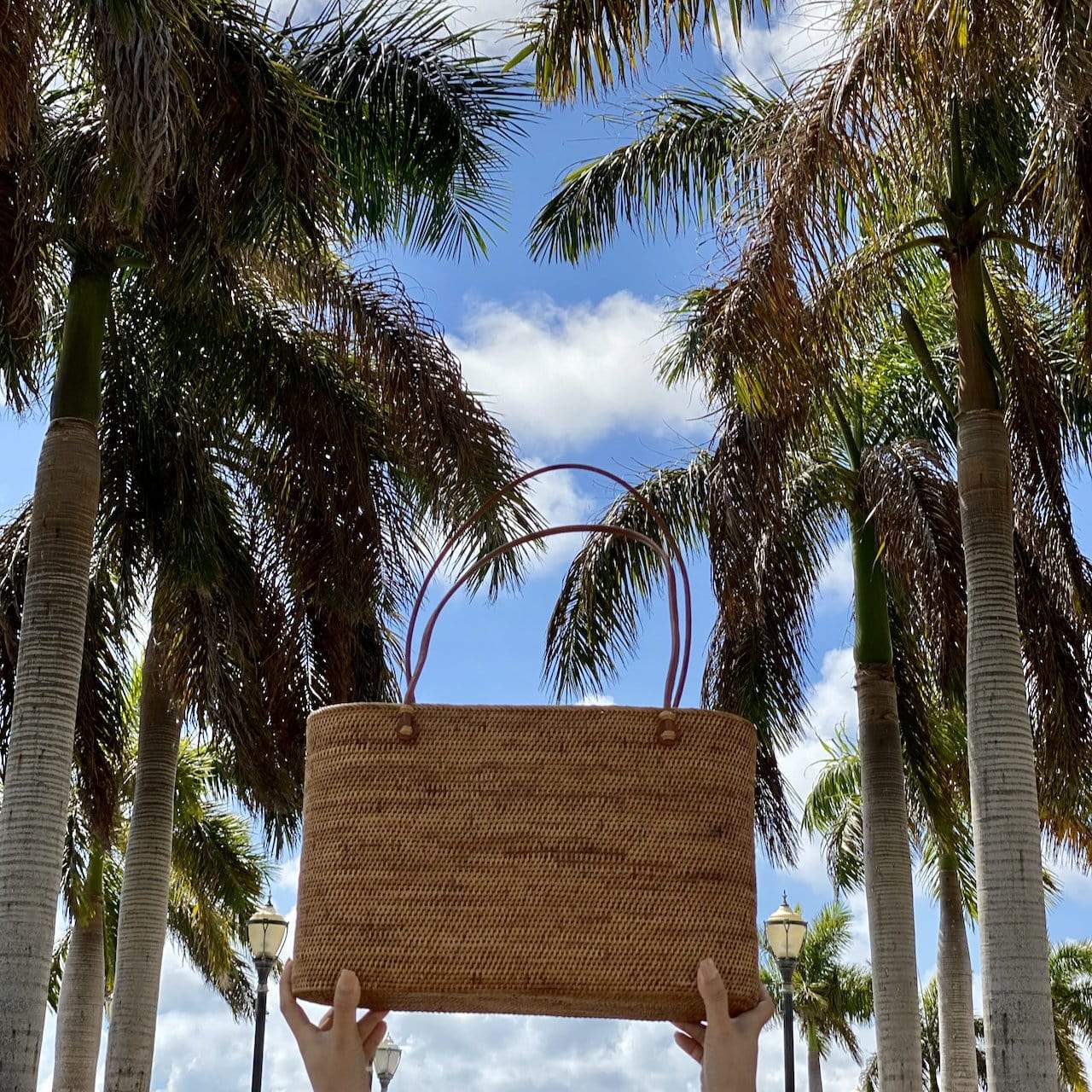 two hands are holding a Bali Rattan Grand Shoulder Bag handmade by Ganapati Crafts Co. in Bali looking stylish