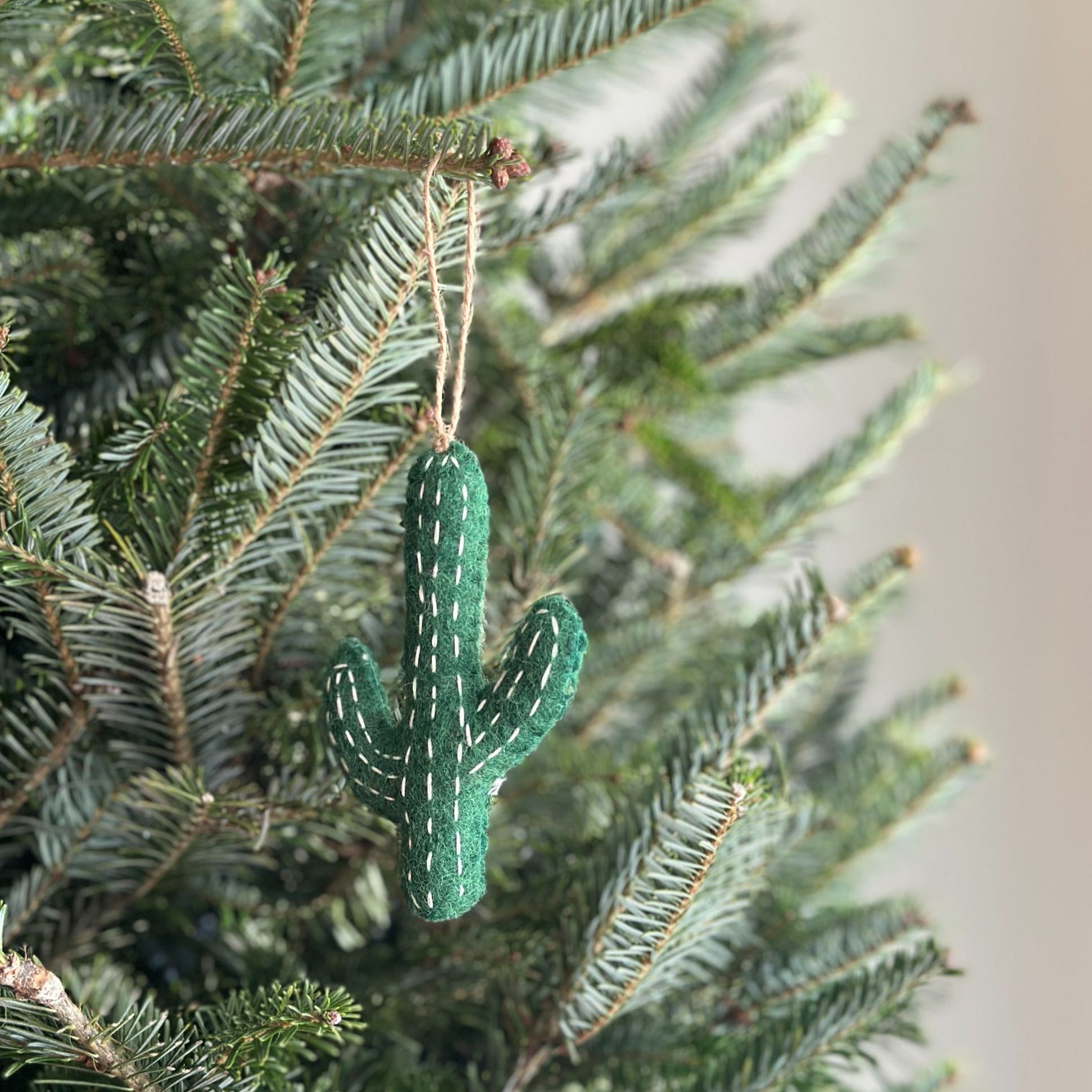 A handmade felt cactus ornaments by Deer Harbour Design hanging on a  Christmas tree