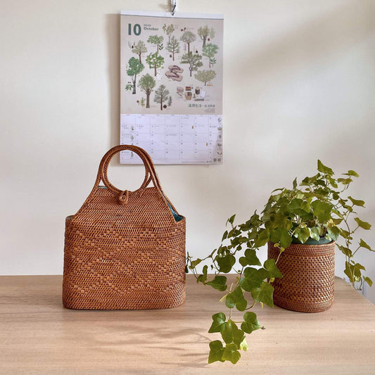 The Tall Malboro Bali Rattan Straw Handbag handmade by Ganapati Craft in Bali where all the Bali Rattan Straw Bags are made is sitting on a table looking stylish