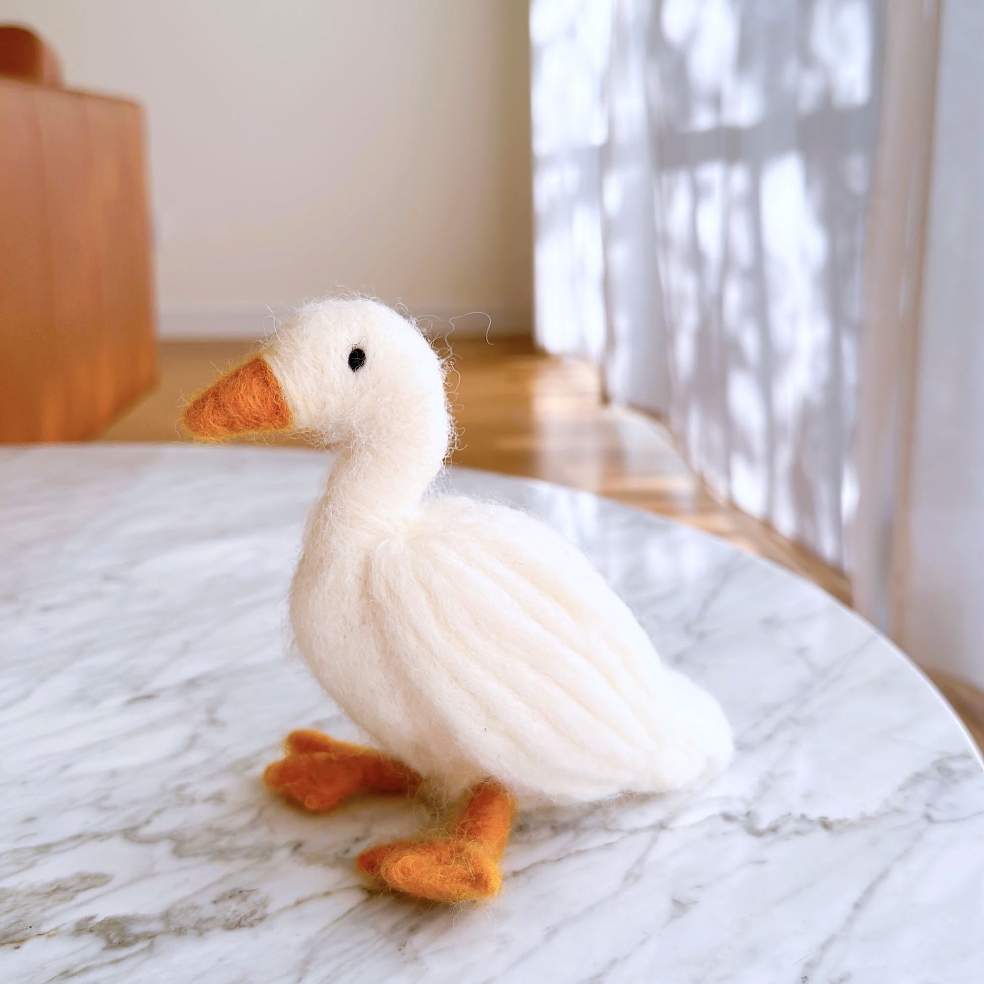 Needle Felted Duck Christmas Ornament handmade by Ganapati Crafts Co. in Nepal sitting on a white table waiting to be put on a Christmas tree