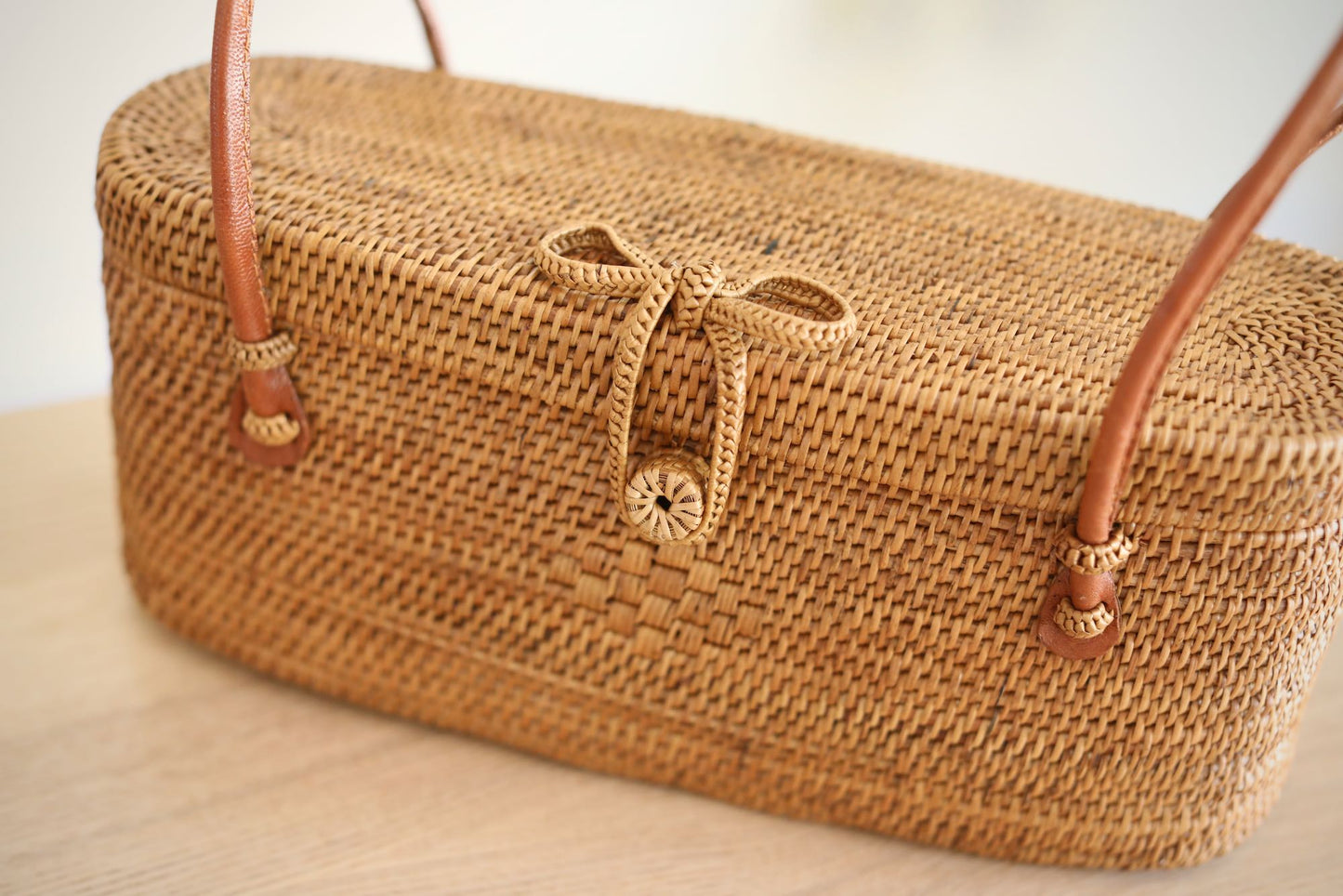 Underarm Bali Rattan Bag handmade by Ganapati Crafts Co. in Bali sitting on a wood table looking amazing for stylish women