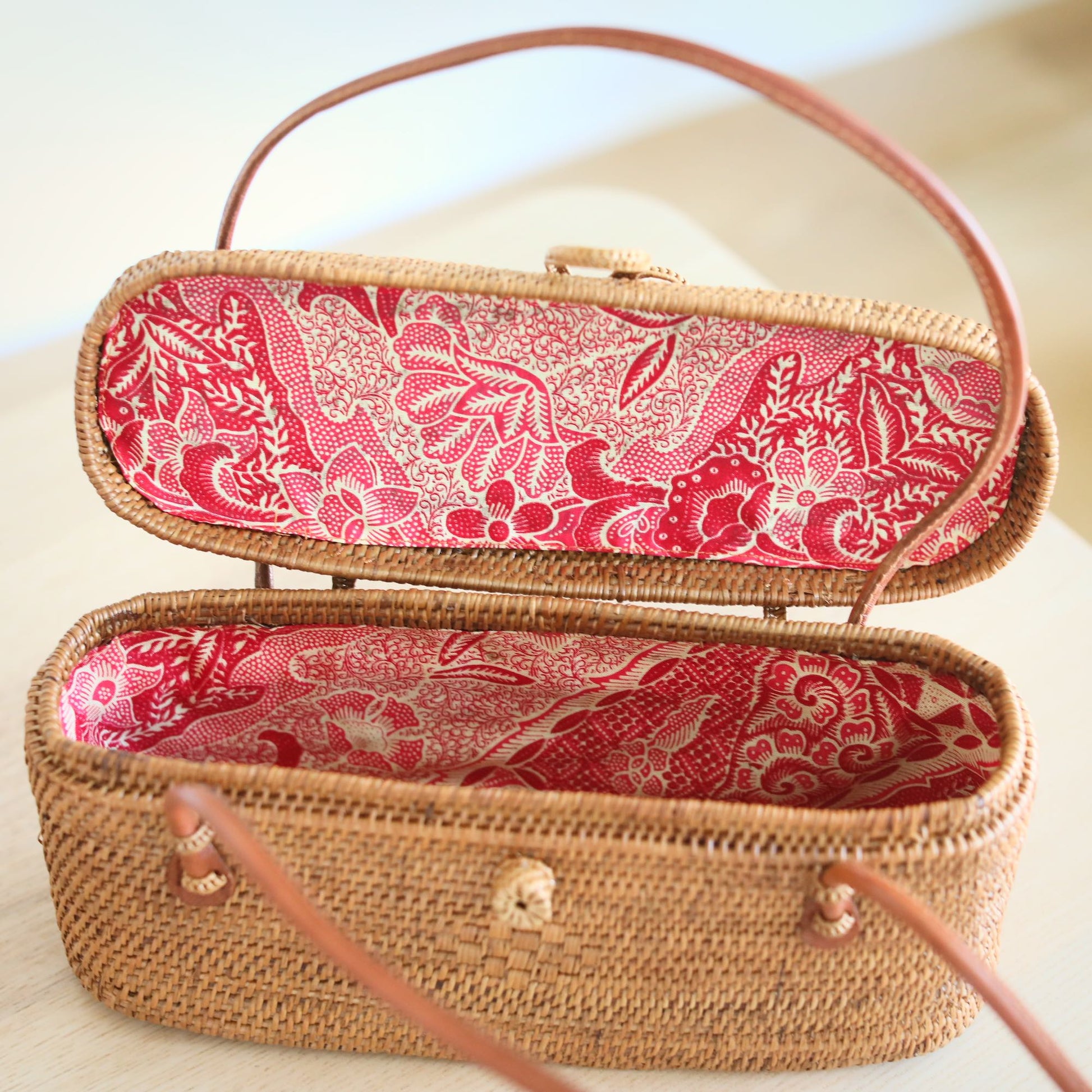 Underarm Bali Rattan Bag handmade by Ganapati Crafts Co. in Bali sitting on a wood table looking amazing for stylish women