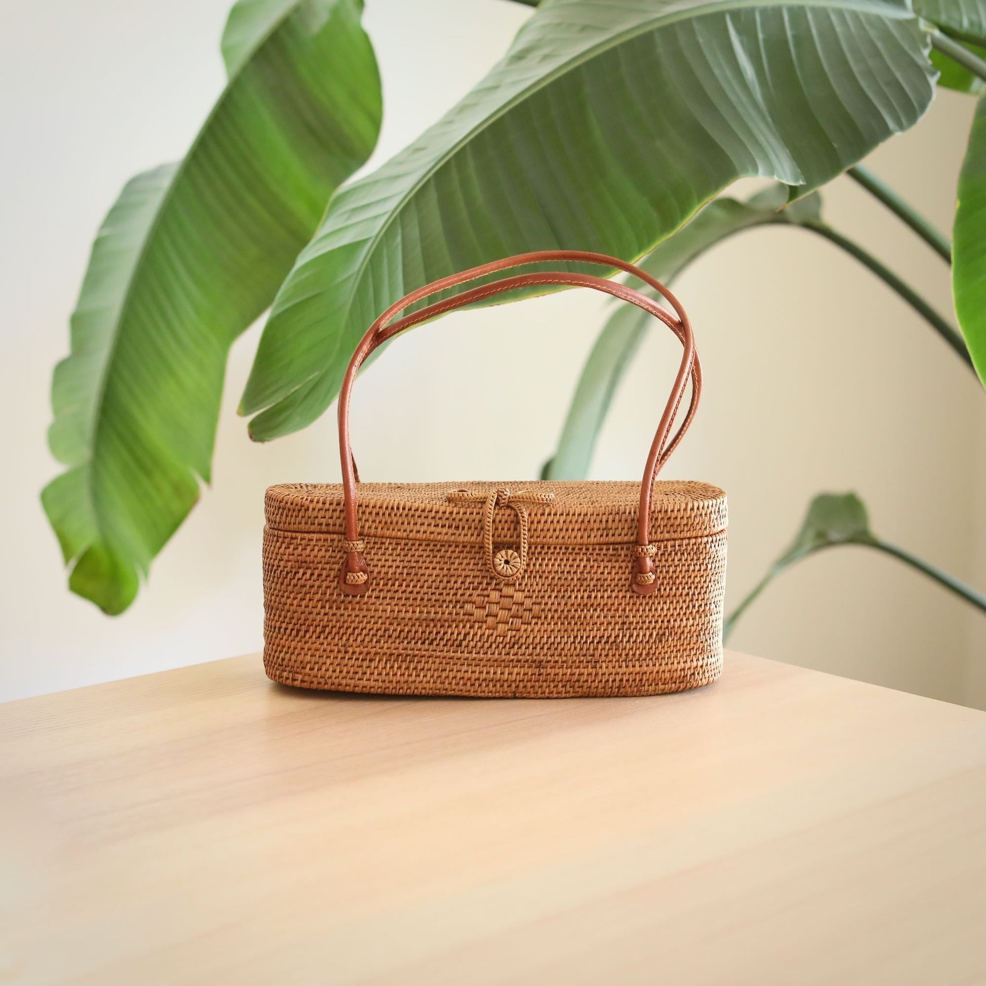 Underarm Bali Rattan Bag handmade by Ganapati Crafts Co. in Bali sitting on a wood table looking amazing for stylish women